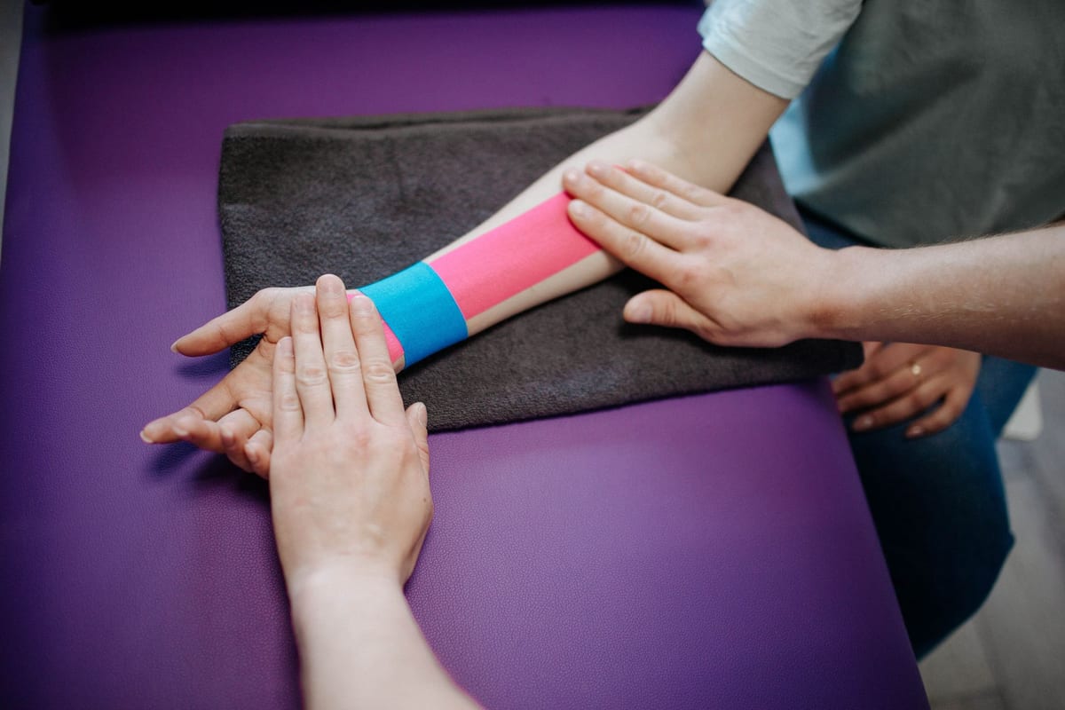 Kinesio tape being applied along a patient's forearm